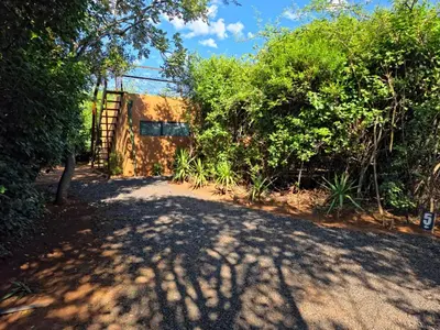 a dirt road with trees and a building in the background at Hartbeest Bush Stay #5 in Hartbeespoort