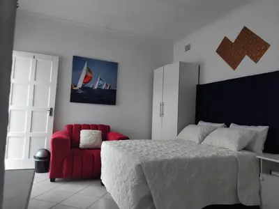 a bedroom with a bed and a red chair at Claremont Secured Residence in Pretoria