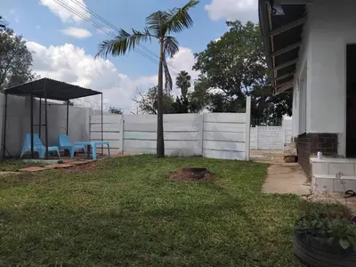 a yard with two chairs and a palm tree and a fence at Claremont Secured Residence in Pretoria