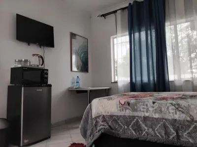 a bedroom with a bed and a flat screen tv at Claremont Secured Residence in Pretoria