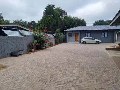 a driveway with a car parked in front of a house at Shabi's Guest Lodge in Phalaborwa