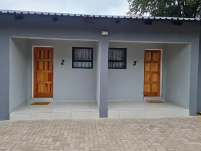 two doors on a white house with a courtyard at Shabi's Guest Lodge in Phalaborwa