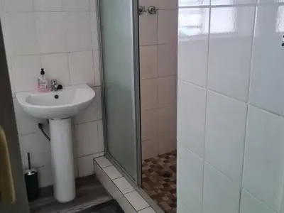 a bathroom with a sink and a shower at Shabi's Guest Lodge in Phalaborwa
