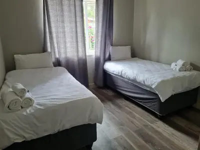 two twin beds in a room with a window at Shabi's Guest Lodge in Phalaborwa