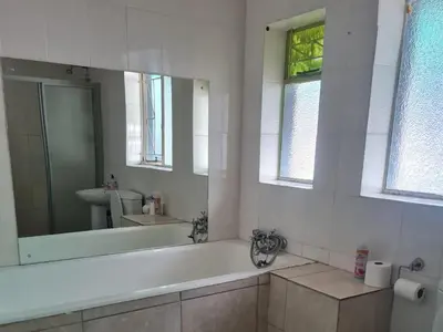 a bathroom with a tub and a sink and a mirror at Shabi's Guest Lodge in Phalaborwa