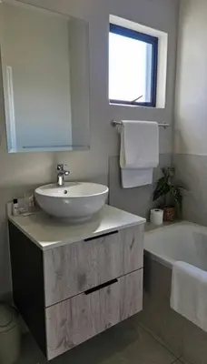 a bathroom with a sink and a tub and a mirror at The Sactuary in Midrand