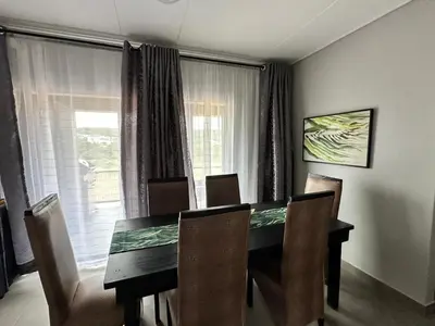 a dining room with a table and chairs and a window at MAYAMUYE Lifestyles in Nelspruit