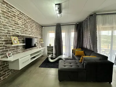 a living room with a couch and a brick wall at MAYAMUYE Lifestyles in Nelspruit