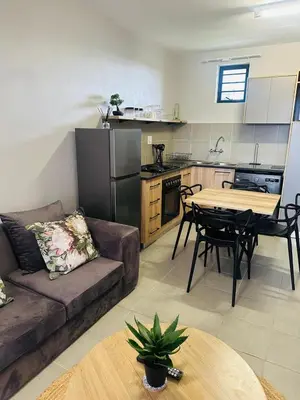 a living room with a couch and a table and a kitchen at Calm & Cozy Apartment in Pretoria