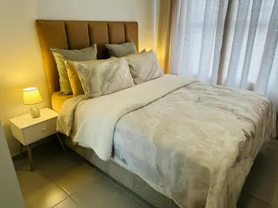 a bedroom with a large bed with a night stand at Calm & Cozy Apartment in Pretoria