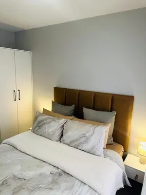 a bedroom with a large bed with white sheets and pillows at Calm & Cozy Apartment in Pretoria