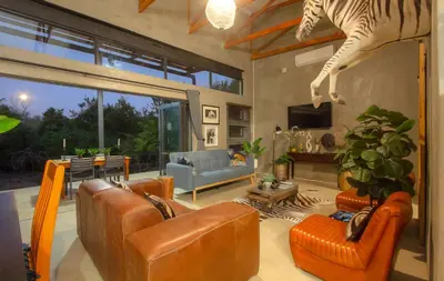 a living room with leather furniture and a zebra statue at IHLATHi Glass Dome in Marloth Park