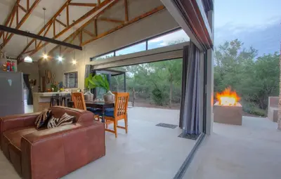 a living room with a couch and a fireplace at IHLATHi Glass Dome in Marloth Park