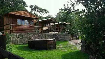 a log cabin with a green yard next to a building at Inniberg Nylstroom Chalets in Modimolle