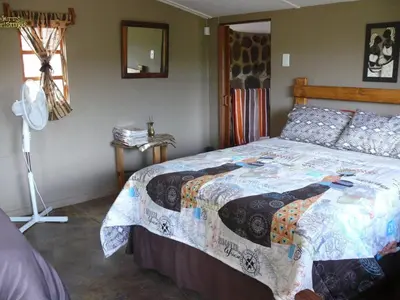 a bedroom with a bed with a quilt on it at Inniberg Nylstroom Chalets in Modimolle