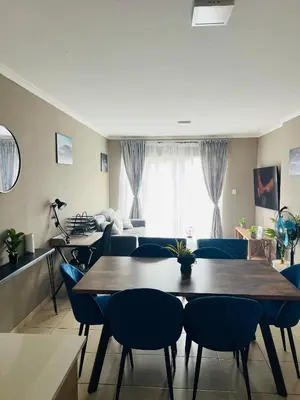 a living room with a table and chairs and a couch at Hartmanz Laxury Apartments in Pretoria