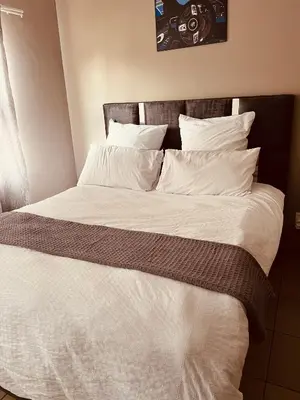 a large bed with white sheets and pillows at Hartmanz Laxury Apartments in Pretoria