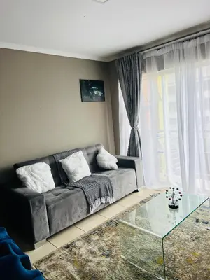 a living room with a couch and a glass table at Hartmanz Laxury Apartments in Pretoria