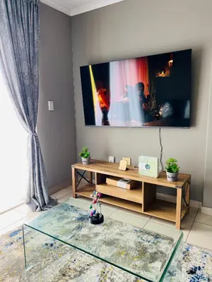 a living room with a tv and a glass table at Hartmanz Laxury Apartments in Pretoria