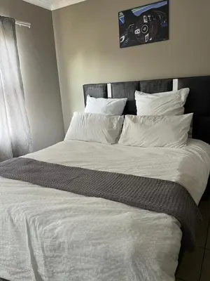 a large bed with white sheets and pillows at Hartmanz Laxury Apartments in Pretoria