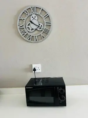 a clock hanging on a wall above a microwave at Hartmanz Laxury Apartments in Pretoria
