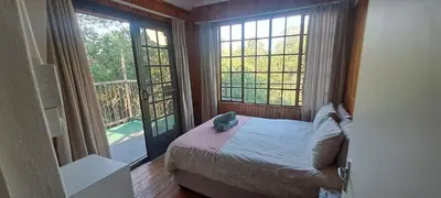 a bedroom with a bed and two large windows at Ratel Retreat in Marloth Park