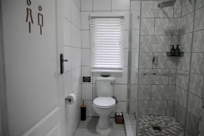 a white bathroom with a toilet and a shower at Reveuse in Pretoria