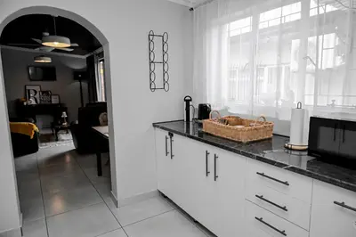 a kitchen with white cabinets and a black counter top at Reveuse in Pretoria