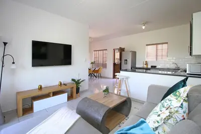 a living room with a couch and a tv on a wall at VH Apartments have fun with us in Midrand