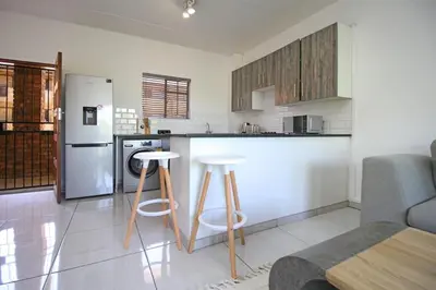 a kitchen with a counter and two stools in it at VH Apartments have fun with us in Midrand