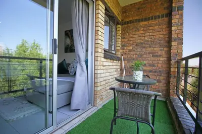a patio with a table and chairs on a balcony at VH Apartments have fun with us in Midrand