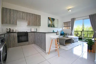 a kitchen with a counter and a living room at VH Apartments have fun with us in Midrand