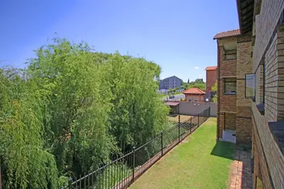 a balcony of a building with a fence and trees at VH Apartments have fun with us in Midrand