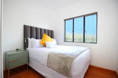 a bedroom with a large white bed with a window at VH Apartments have fun with us in Midrand