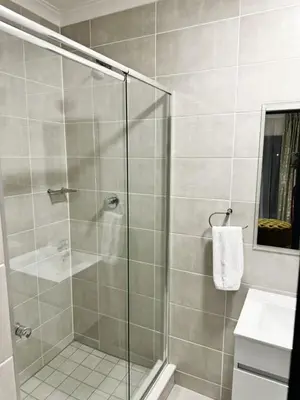 a bathroom with a glass shower with a sink at Joe's The Blyde in Pretoria