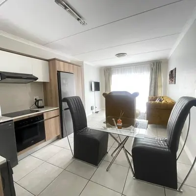a living room with a glass table and chairs at Joe's The Blyde in Pretoria