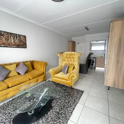 a living room with a yellow couch and a chair at Joe's The Blyde in Pretoria