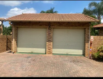 a garage with two doors on a brick driveway at Tendani Full-House in Centurion