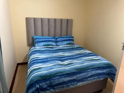 a bed with a blue comforter in a bedroom at Tendani Full-House in Centurion