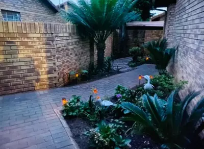 a garden with plants and lights on a brick wall at Tendani Full-House in Centurion
