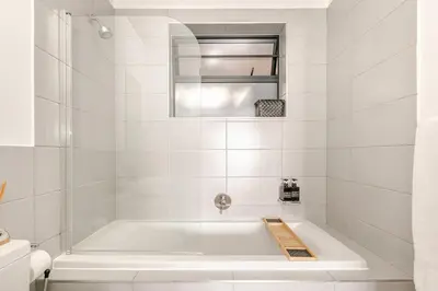 a white bathroom with a tub and a mirror at Cityescapes 2F in Waterfall Midrand - Beautiful self catering 2 bedroom unit next to Kyalami Racetrack with free WiFi swimming pool gym and restaurant - Perfect for a small family in Midrand