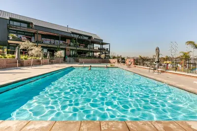 a large swimming pool in front of a building at Cityescapes 2F in Waterfall Midrand - Beautiful self catering 2 bedroom unit next to Kyalami Racetrack with free WiFi swimming pool gym and restaurant - Perfect for a small family in Midrand