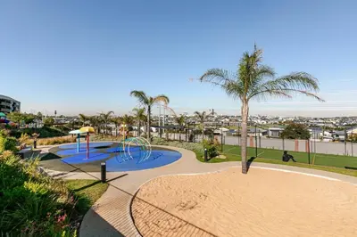 a park with a playground with a slide and palm trees at Cityescapes 2F in Waterfall Midrand - Beautiful self catering 2 bedroom unit next to Kyalami Racetrack with free WiFi swimming pool gym and restaurant - Perfect for a small family in Midrand