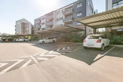 a parking lot with cars parked in front of a building at Cityescapes 2F in Waterfall Midrand - Beautiful self catering 2 bedroom unit next to Kyalami Racetrack with free WiFi swimming pool gym and restaurant - Perfect for a small family in Midrand
