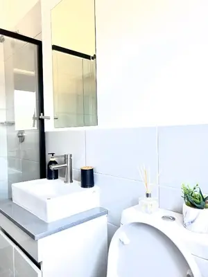 a white bathroom with a sink and a mirror at Stylish Waterfall Apartment -Braai ,Fast WiFi, Pool in Midrand