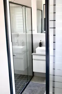 a bathroom with a glass shower and a sink at Stylish Waterfall Apartment -Braai ,Fast WiFi, Pool in Midrand