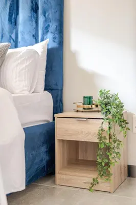 a wooden bedside table with a plant next to a bed at Stylish Waterfall Apartment -Braai ,Fast WiFi, Pool in Midrand