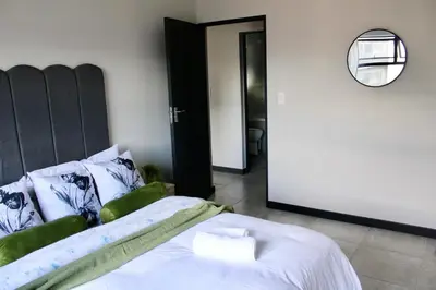 a bedroom with a bed with a black headboard and a mirror at Stylish Waterfall Apartment -Braai ,Fast WiFi, Pool in Midrand