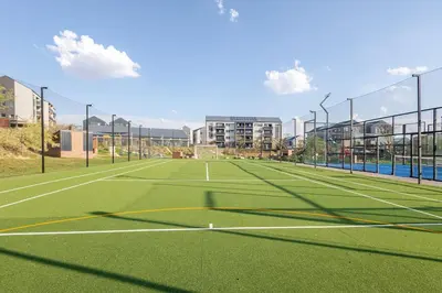 a tennis court in front of a building at Stylish Waterfall Apartment -Braai ,Fast WiFi, Pool in Midrand