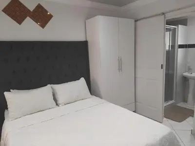 a bedroom with a white bed and a bathroom at Claremont Secured Accommodation in Pretoria